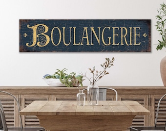May include: A rectangular wall sign featuring a dark navy blue background with a distressed, crackled finish. The word BOULANGERIE is displayed in large, gold-coloured serif lettering across the centre, flanked by small decorative gold arrow icons.