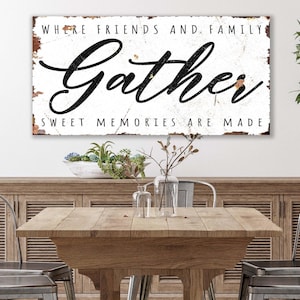 May include: A rectangular wall sign with a white distressed finish and rust-colored edges. The sign features the black text "WHERE FRIENDS AND FAMILY" at the top, the word "Gather" in a large script font in the center, and "SWEET MEMORIES ARE MADE" at the bottom.