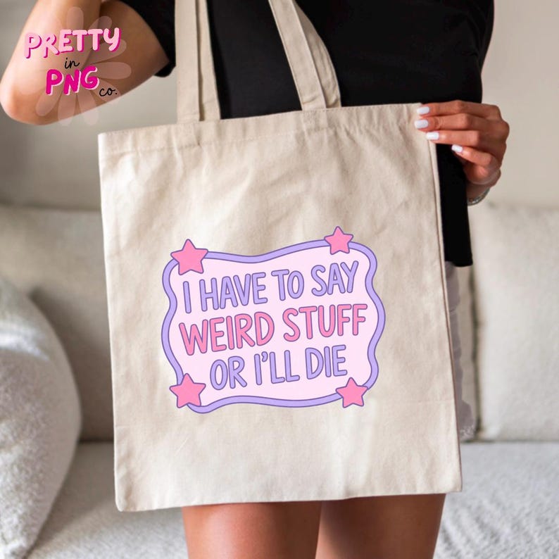 May include: Beige tote bag with the text "I HAVE TO SAY WEIRD STUFF OR I'LL DIE" in a purple and pink design. The bag has two handles and is held by a person. The bag has a simple, casual design.