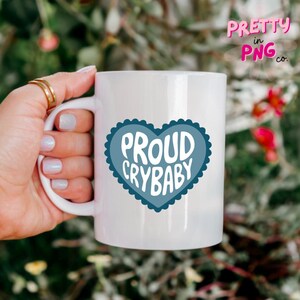 May include: White ceramic mug with a blue heart design that says "Proud Crybaby".