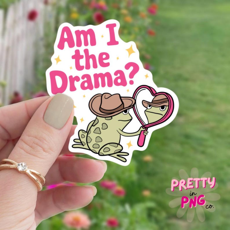 Pode incluir: Um adesivo rosa com um sapo de desenho animado usando um chap&eacute;u de cowboy e segurando um espelho em forma de cora&ccedil;&atilde;o. O sapo est&aacute; olhando para seu reflexo no espelho. O texto "Am I the Drama?" est&aacute; escrito acima do sapo.