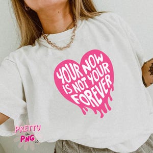 Puede incluir: Camiseta blanca con un gr&aacute;fico de coraz&oacute;n rosa que dice "Your Now Is Not Your Forever".