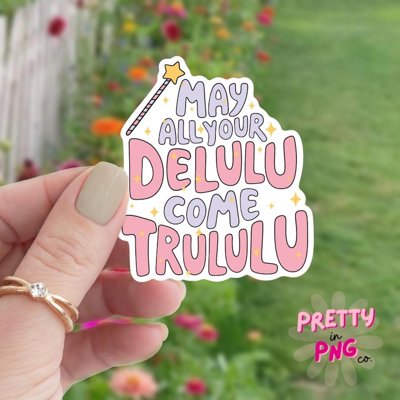 Pode incluir: Um adesivo rosa e branco com uma varinha m&aacute;gica e o texto "May all your Delulu come Trululu".