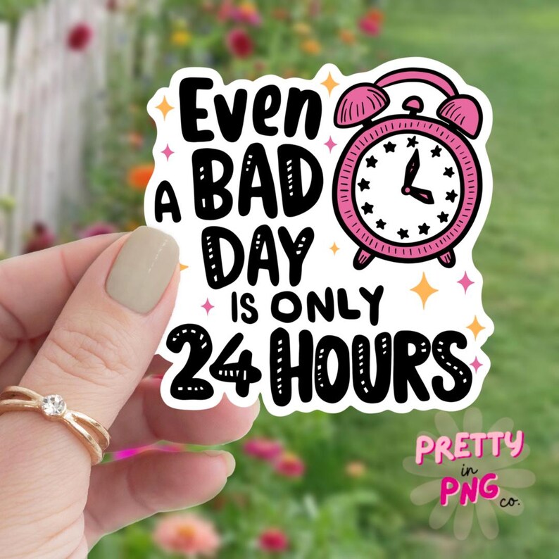 May include: White sticker with black text that reads "Even a bad day is only 24 hours". A pink alarm clock with black hands and black stars is next to the text. The sticker has a white border and a glittery background.