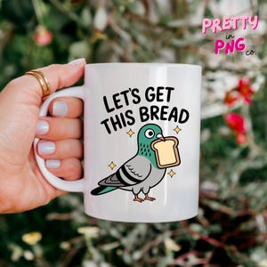 Może przedstawiać: Biały ceramiczny kubek z napisem "LET'S GET THIS BREAD" i rysunkiem gołębia trzymającego kromkę chleba. Gołąb jest turkusowy, szary i czarny, z ż&oacute;łtymi gwiazdkami. Kubek ma biały uchwyt.