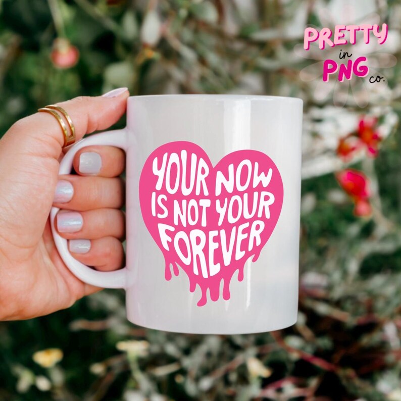 Puede incluir: Taza de cer&aacute;mica blanca con un dise&ntilde;o de coraz&oacute;n rosa. El coraz&oacute;n tiene el texto "Your now is not your forever" en letras blancas.