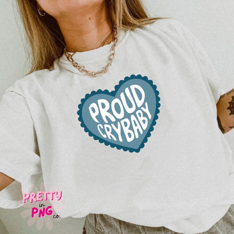May include: White t-shirt with a blue heart graphic that says "Proud Crybaby".