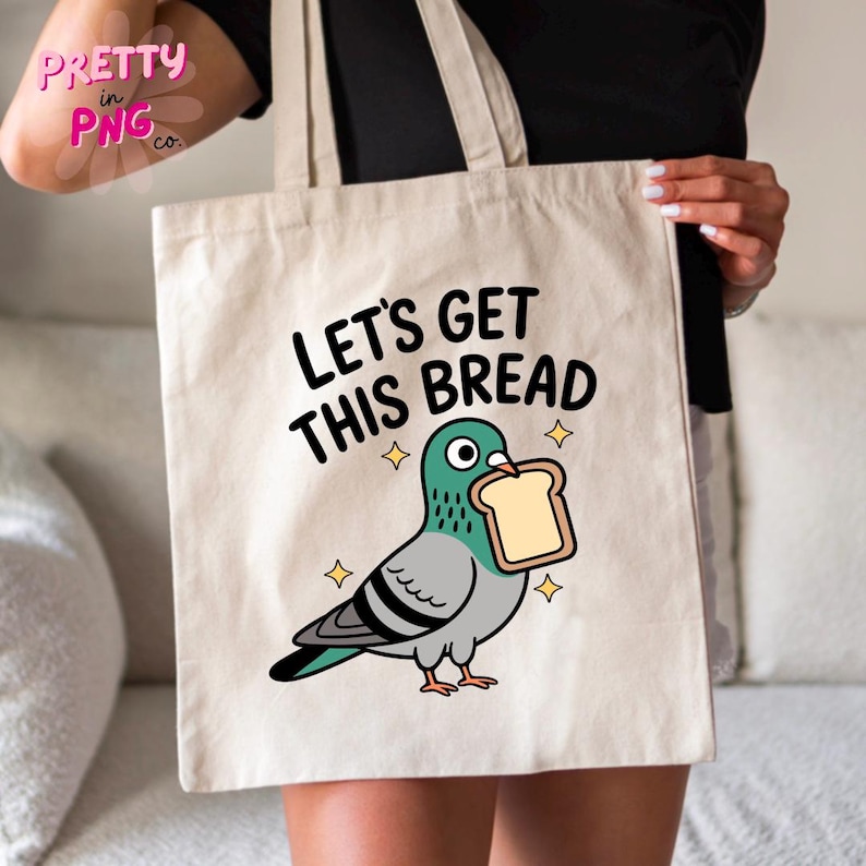 Może przedstawiać: Beżowa torba z napisem "LET'S GET THIS BREAD" i kresk&oacute;wkowym gołębiem trzymającym kromkę chleba. Gołąb jest szary, turkusowy i czarny, z ż&oacute;łtymi gwiazdkami. Torba ma dwa uchwyty.