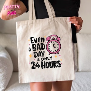 May include: A white tote bag with a pink alarm clock graphic and the text "Even a bad day is only 24 hours".
