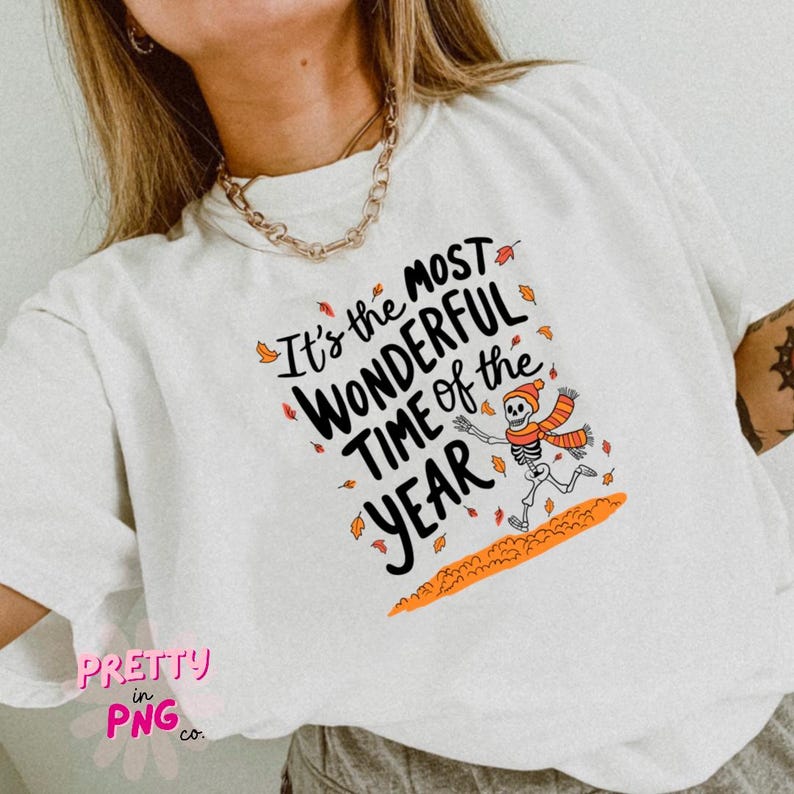 May include: White t-shirt with the text "It's the most wonderful time of the year" and a skeleton wearing a scarf and running through autumn leaves.
