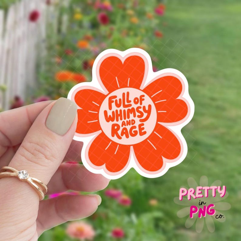 Może przedstawiać: Naklejka w kształcie kwiatu z pomarańczowymi płatkami i napisem "Full of Whimsy and Rage" w kolorze białym i pomarańczowym. Naklejka jest trzymana na tle rozmytego kwiatowego tła.