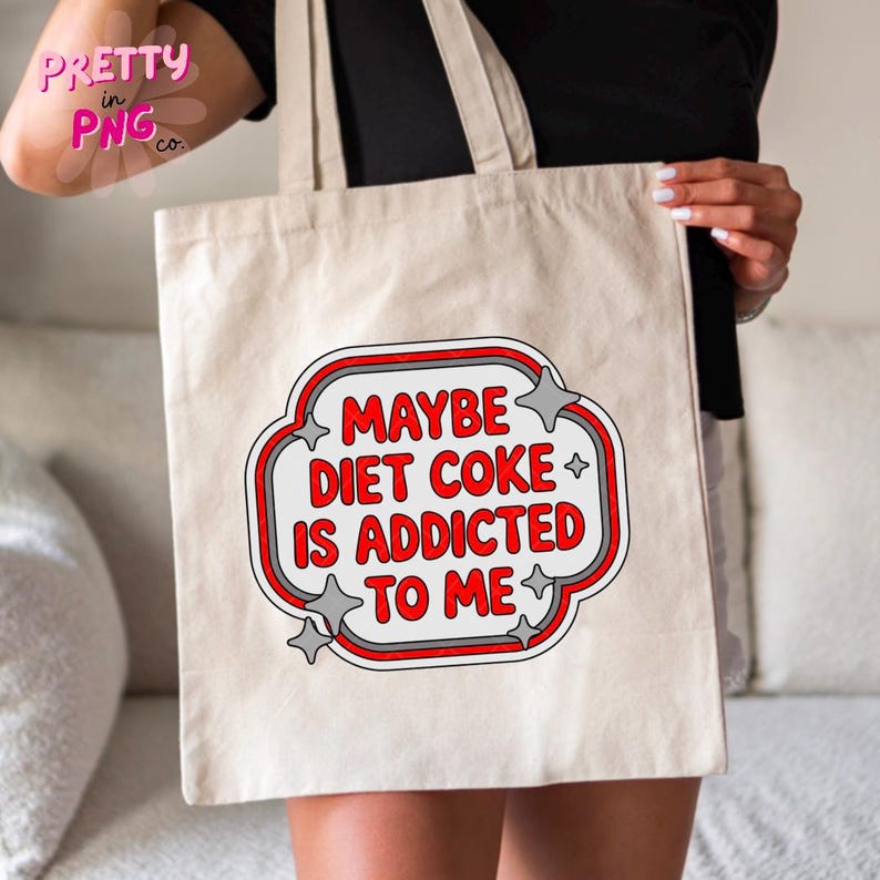May include: Beige tote bag with the text "MAYBE DIET COKE IS ADDICTED TO ME" in a red and white design. The text is inside a white and red outlined shape with star accents. The bag has two handles.