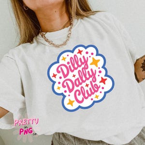 May include: A white short-sleeve t-shirt featuring a central graphic with the pink text Dilly Dally Club inside a white cloud-like shape with a blue outline, surrounded by small red and yellow star icons and dots on a light-colored fabric.