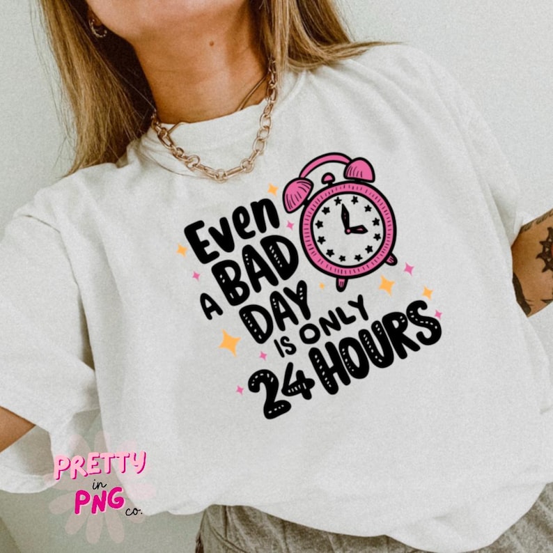 May include: White t-shirt with a pink alarm clock graphic and the text "Even a bad day is only 24 hours".
