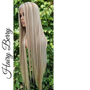 May include: A long, straight blonde wig with highlights in a lighter shade of blonde. The wig is styled with a centre parting and falls to the shoulders.