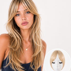 May include: A woman with long, layered blonde hair and bangs, wearing a navy blue tank top. A small, gold pendant necklace is visible. A separate image shows a blonde hairpiece with bangs on a mannequin head.