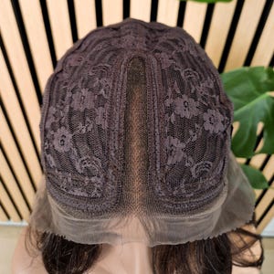 K&ouml;nnte beinhalten: Eine braune Per&uuml;cke mit einem Spitzenfront und einem Spitzenverschluss. Die Per&uuml;cke befindet sich auf einem Mannequin-Kopf.