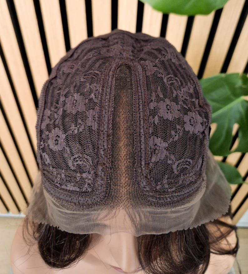 K&ouml;nnte beinhalten: Eine braune Per&uuml;cke mit einem Spitzenfront und einem Spitzenverschluss. Die Per&uuml;cke befindet sich auf einem Mannequin-Kopf.