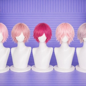 Peut inclure: Cinq perruques aux tons roses et violets sont exposées sur des têtes de mannequins blanches. Les perruques ont différents styles, dont des coupes courtes et effilées et une couleur magenta vibrante. Les mannequins sont sur des socles circulaires blancs sur fond violet rayé.