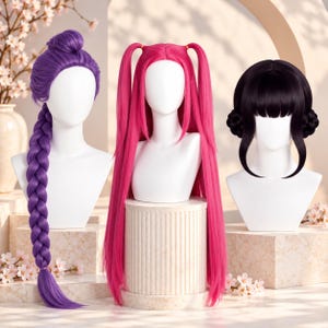 May include: Three synthetic wigs displayed on white mannequin heads. The left wig is purple with a high bun and a long, thick braid. The centre wig is bright pink with two long pigtails. The right wig is black with bangs and two side buns.