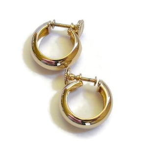 May include: A pair of gold-toned hoop earrings with a screw-on closure. The earrings have a polished, rounded design and are set against a white background. The screw mechanism is visible at the top of each earring.