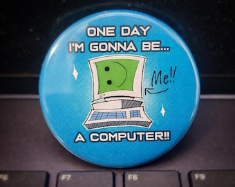 May include: A round, light blue button with the text "ONE DAY I'M GONNA BE... A COMPUTER!!" and a cartoon computer with a smiley face. The button has a white border and two small star-shaped sparkles.