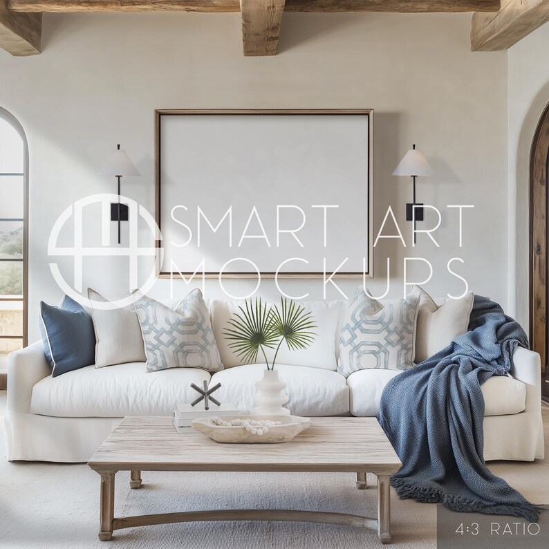 Beach House Art Display Mockup: This light-filled, blue-accented living space features a blank frame over a white linen sofa, for beach-themed or ocean-inspired art displays. Blank canvas frame on the wall ready for your artwork.