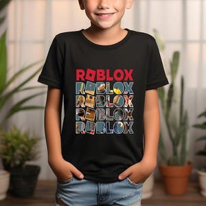 May include: Black t-shirt featuring the word "ROBLOX" in red and white block letters. Below, the word "ROBLOX" is repeated four times, each letter filled with different images. The shirt is worn by a child.
