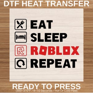 May include: White DTF heat transfer with the text "EAT SLEEP ROBLOX REPEAT" in black and red. The Roblox logo is red. The transfer also includes icons for eating, sleeping, and repeating. The words "READY TO PRESS" are at the bottom.