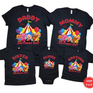 May include: Black t-shirts with colorful circus-themed graphics. The shirts read "Daddy," "Mommy," "Sister," and "Brother" with "Birthday Boy" below. A onesie reads "Oliver." The graphics include cartoon characters, balloons, and a circus tent.