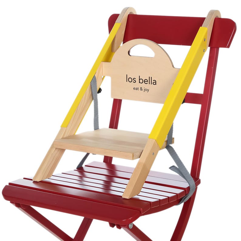 May include: A red and natural wood high chair with yellow safety straps. The chair has a wooden seat and backrest, with the text "los bella eat & joy" printed on the back.