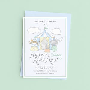 May include: A light blue invitation card with a circus theme. The card features a circus tent, an elephant balancing on a ball, and the text "Hampton's Three Ring Circus!" The invitation is on a light blue envelope.
