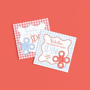 May include: Two Valentine's Day cards with a red and blue gingham pattern. Each card features a fidget spinner design and the text "Valentine, You Make My Heart Spin!" and "Your Friend, Bo."