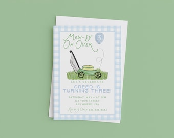 May include: A rectangular birthday invitation card with a light blue gingham border. The text reads MOW-SY ON OVER, LET'S CELEBRATE CREED IS TURNING THREE, SATURDAY, MAY 6 AT 2PM, 123 YOUR STREET, ANYWHERE, USA, REGRETS ONLY 555-555-5555. Features a lawnmower illustration.