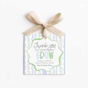 May include: A square gift tag with a beige ribbon bow. The tag has a light blue and green floral design with the words "Thank you for helping me GROW" and "Happy Teacher Appreciation Week!" printed on it.