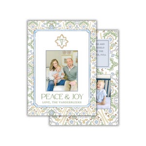 Op de afbeelding: Kerstkaarten met een familiefoto in een blauwe lijst. De kaarten hebben een bloemenpatroon in groen, blauw en goud. De tekst "PEACE & JOY" en "LOVE, THE VANDERBLEEKS" staat op de voorkant.