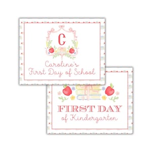 Pode incluir: Dois cartões brancos com detalhes vermelhos e rosados. O cartão superior tem um desenho floral rosa e branco com a letra "C" no centro. O texto "Caroline's First Day of School" está impresso em vermelho. O cartão inferior tem uma maçã vermelha, livros e o texto "FIRST DAY of Kindergarten" impresso em vermelho.