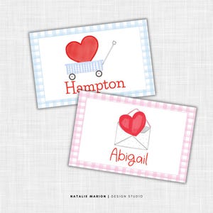 May include: Two watercolor-style cards with a white background and gingham borders. One card has a red heart in a blue wagon with the name "Hampton". The other card has a red heart in an envelope with the name "Abigail".