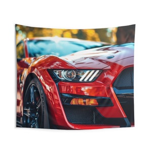May include: A close-up of a red Ford Mustang Shelby GT500 with black accents. The car's front headlight and grille are in focus, showcasing the car's aggressive design.