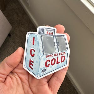 May include: A sticker featuring a cartoon ice chest design with the words "ICE COLD" in red. The sticker also includes the text "Tweeprise Fest" and "SPAC N3 2025". The ice chest has a light blue and white color scheme.