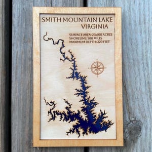 Könnte beinhalten: Ein rechteckiges Wandbild aus Holz mit einer lasergeschnittenen Karte des Smith Mountain Lake, Virginia. Der See ist mit dunkelblauem Harz gefüllt. Der Text enthält Angaben zur Fläche von 20.600 Acres, 500 Meilen Uferlinie und 220 Fuß Tiefe.