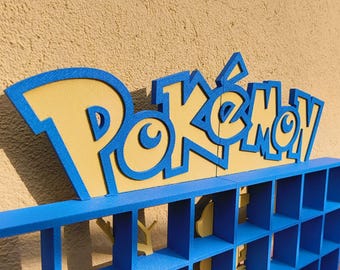 May include: A blue and yellow Pokemon themed shelf unit with multiple compartments. The top of the shelf has a 3D Pokemon logo.