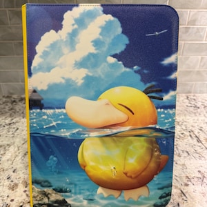 Pode incluir: Uma capa protetora retangular para tablet com um gráfico vibrante de uma criatura amarela semelhante a um pato parcialmente submersa em água azul clara. A cena inclui um céu azul com nuvens brancas, uma silhueta distante e rochas.