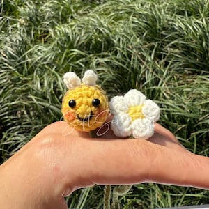 Puede incluir: Una abeja y una flor hechas a mano con ganchillo. La abeja es amarilla con antenas blancas y ojos negros. La flor es blanca con el centro amarillo. Los art&iacute;culos son peque&ntilde;os y artesanales.