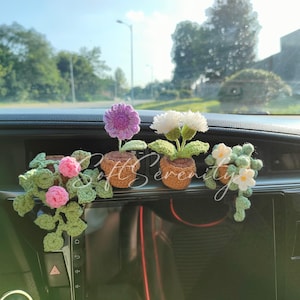 May include: Crocheted flower arrangements in small brown pots. The flowers are purple, white, pink, and white with yellow centers. Green leaves and vines are also included. The text "Soft Serenity" is written across the image.