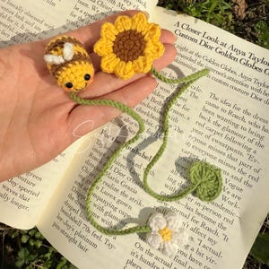 Puede incluir: Juego de marcap&aacute;ginas de abeja y girasol de ganchillo. La abeja es amarilla y marr&oacute;n con alas blancas, y el girasol es amarillo y marr&oacute;n. El tallo del marcap&aacute;ginas es verde con una margarita blanca y una hoja verde.