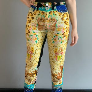 Peut inclure: Jean taille haute &agrave; motifs avec un design unique. Le jean pr&eacute;sente une base jaune avec un imprim&eacute; l&eacute;opard, des motifs floraux et des illustrations. Des pi&egrave;ces de tissu bleu et noir sont int&eacute;gr&eacute;es au design.