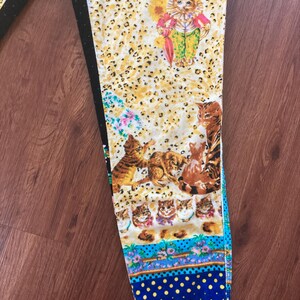 Peut inclure: Un pantalon &agrave; motifs avec un motif de chat fantaisiste. Le pantalon a un fond jaune &agrave; imprim&eacute; l&eacute;opard avec diverses illustrations de chats, des accents floraux et une bordure &agrave; pois bleus. Le pantalon est fait d'une mati&egrave;re douce et confortable.