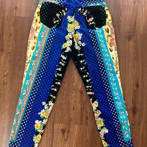 Peut inclure: Jean &agrave; motifs bleus, noirs et jaunes avec des motifs floraux et &agrave; pois. Le jean a une ceinture noire avec un patch en cuir. Le jean a une coupe droite.