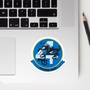 Puede incluir: Una pegatina circular con un diseño azul y blanco, con el número 4 y una criatura parecida a un dragón. El texto "PATRON FOUR" está en una pancarta azul. La pegatina está en un portátil.